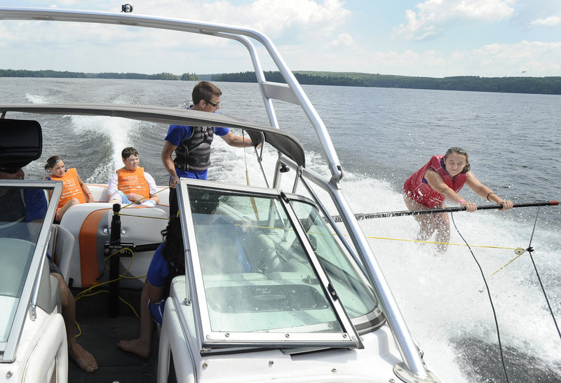 Aria Kneeland, 13, of Windham, skis alongside the In His Wakes program’s boat Tuesday as Jake Miller provides instruction on Little Sebago Lake in Windham.