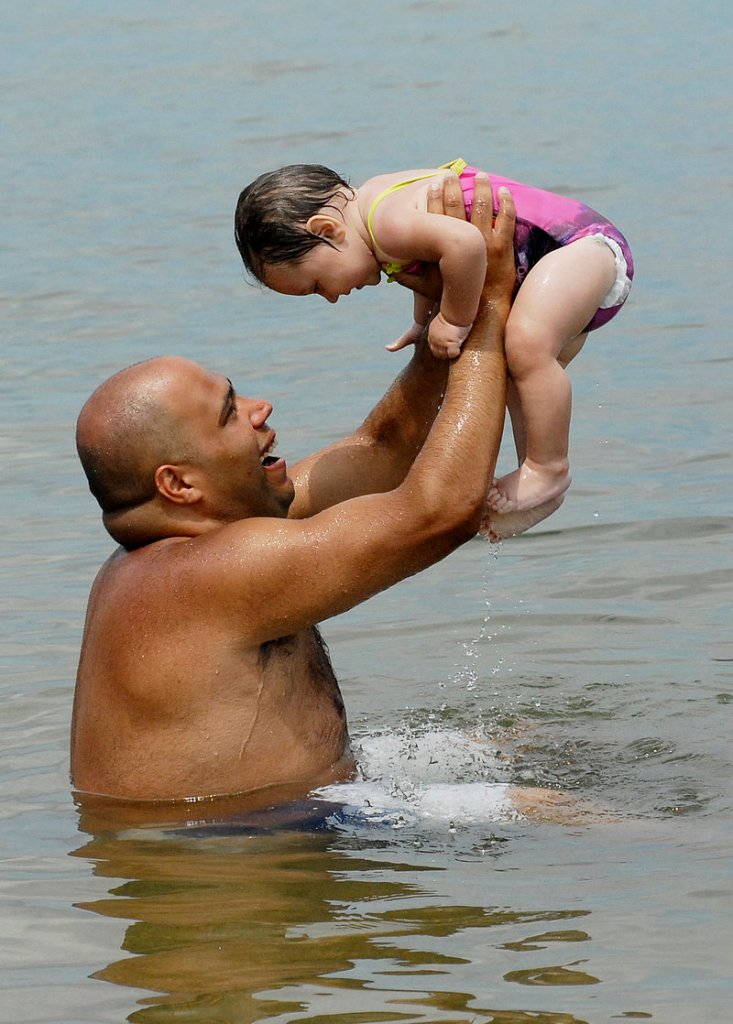 Eloy Figueroa of Portland cools off with 10-month-old Nevaeh Figueroa on Tuesday at East End Beach in Portland.