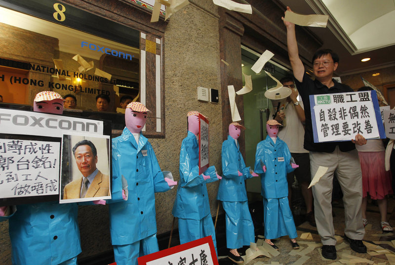 Labor activists throw paper money near figures representing deceased workers at Foxconn Technology Group in Hong Kong. Demands for better wages and working conditions are hastening the eventual end of cheap labor costs in China.