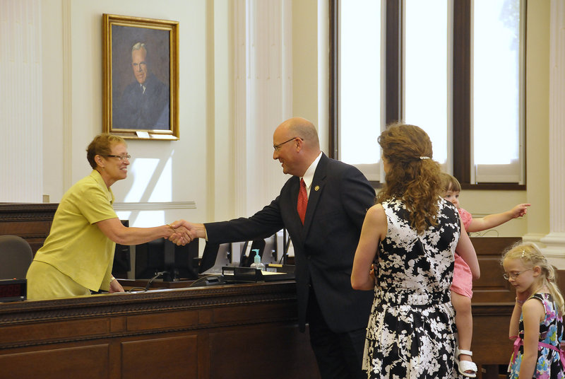 Noel C. March shakes hands with Linda Jacobson, clerk of the United States District Court, with his family at his side.
