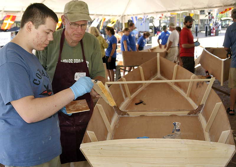 Billy Babin, left, gets help from instructor Fred Fowler as Babin applies glue to a part of a Bevins skiff he is building Monday. The Compass Project gives students from Greater Portland a chance to enjoy boat building and improve their confidence and work ethic.