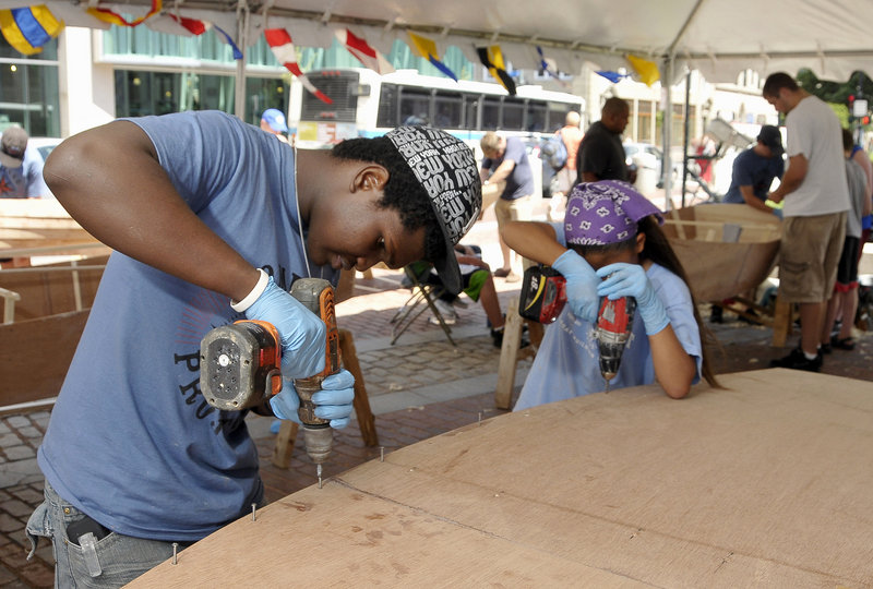 Steeve Francois, 18, of Haiti, screws the bottom plank to the 12-foot Bevins skiff he was helping to build Monday.