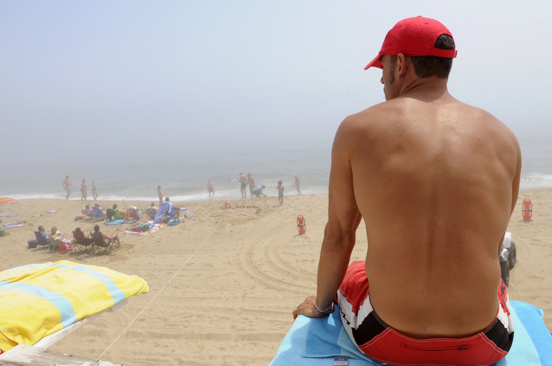Lifeguard Lance Timberlake watches visitors to Old Orchard Beach from a guard tower Tuesday. On Sunday and Monday alone, lifeguards reported 49 incidents in which they had to assist people caught in riptides there. In a more typical week, there are only a few incidents daily.
