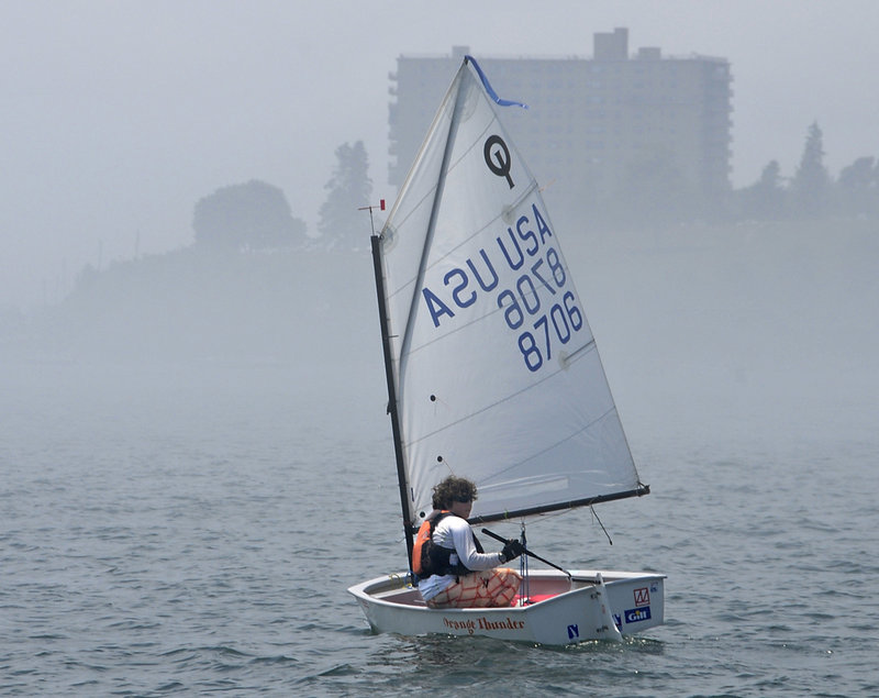Cooper Slepert of the Portland Yacht Club waits out a fog Tuesday off the Eastern Promenade in Portland as the two-day USA Junior Olympic Sailing Festival Northeast championships began.