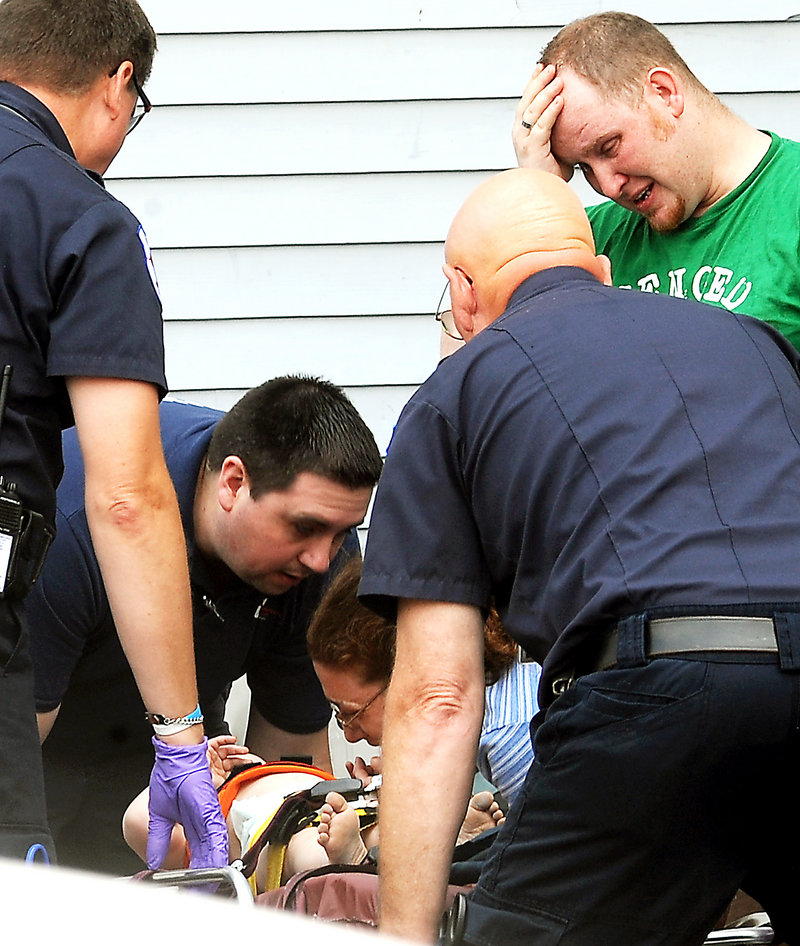 The mother and father of a 22-month-old boy who fell from the third floor of their apartment at 21 Walnut St. in Lewiston, react as their child is about to be loaded by emergency personnel into an ambulance on Tuesday morning. Police said the child had landed in a pile of soft dirt and was conscious when he was taken to Central Maine Medical Center in Lewiston.
