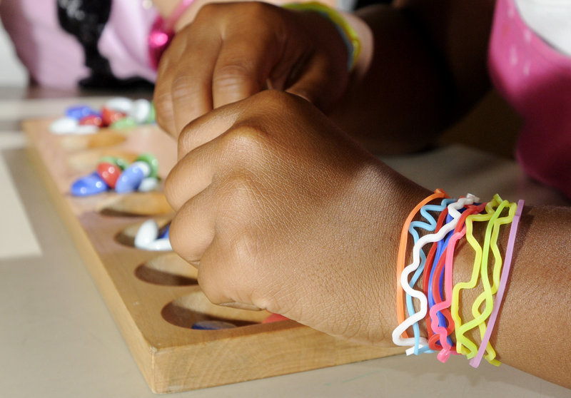 Dominique Hamilton wears her Silly Bandz while playing a game of Mancala. Popularity of the colorful rubber bands that retain specific shapes has exploded. Kids wear, trade and collect them.
