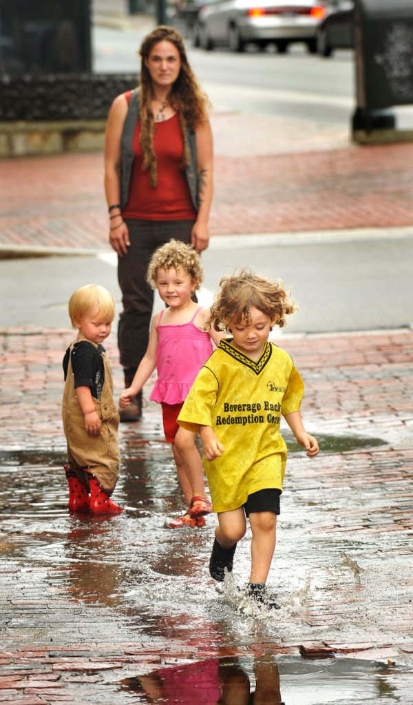 Wyatt Bicycle Kennedy splashes through rain puddles in Portland's Monument Square on Wednesday afternoon while he's watched by his mother, Nicole Niehoff (rear) and friends Seamus Clermont and Amina Edgewood Writer.