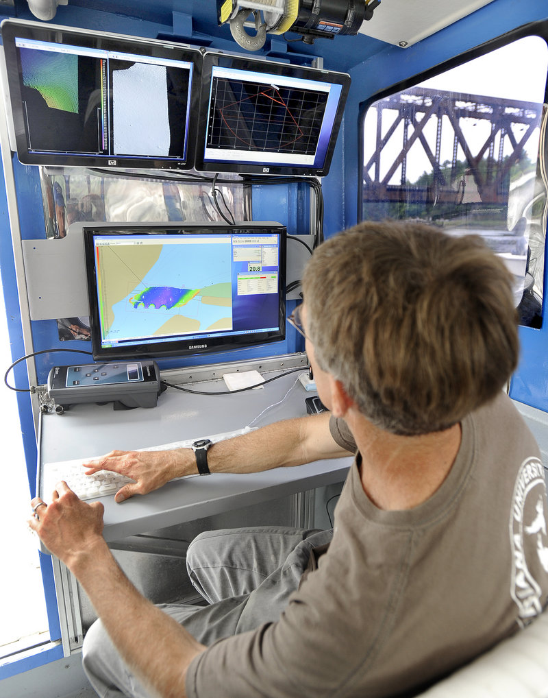 Tom Waddington, chief hydrographer for Substructure Inc. of Portsmouth, N.H., monitors data aboard the Orion, a custom-designed 31-foot aluminum boat, during an underwater survey of the old Sheepscot River railroad bridge in Wiscasset last week.