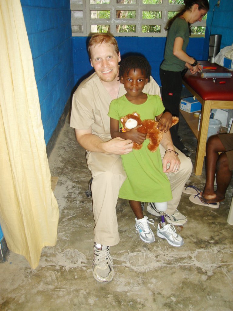 Chris Blades, a prosthetist from Portland who recently spent two weeks in Haiti, poses with a girl he helped fit with a prosthetic leg.