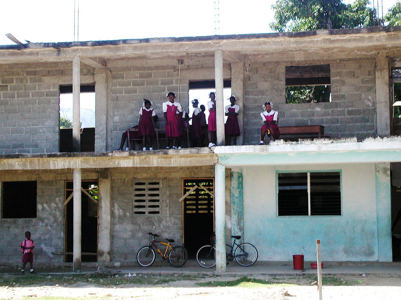 Children stand on the second floor of a school under construction in Haiti that has lacked a roof, doors, windows and second-floor safety railings for about a decade.