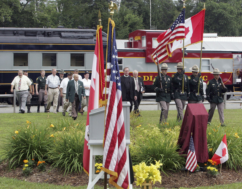 Dignitaries from the United States and Canada follow a New Hampshire state police color guard at a ceremony Friday dedicating a memorial garden to railroad workers from both countries who served in the armed forces and merchant marine.