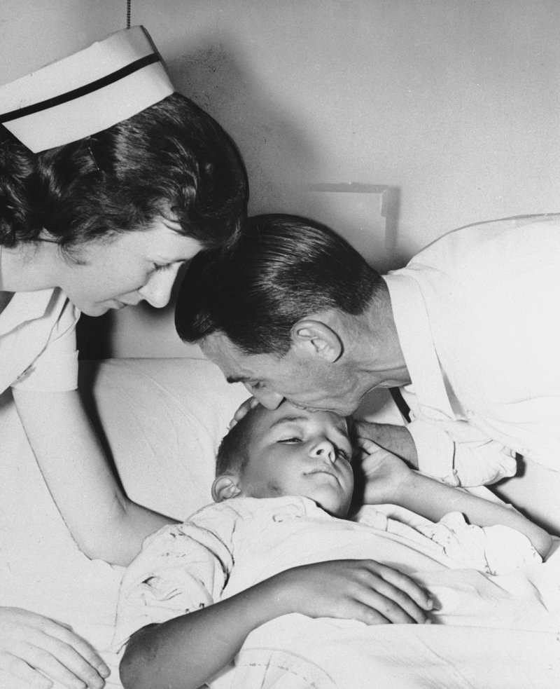 In a photo from July 11, 1960, the 7-year-old Woodward is embraced by his father, George Woodward, at a hospital after the boy survived his 162-foot tumble over Horseshoe Falls.