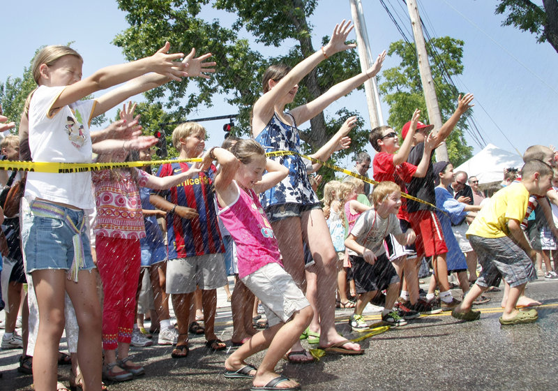 Kids of all ages cool off with spray from the Fireman’s Muster on a hot Saturday.