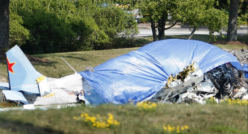 A tarp covers the remains of a Yak-52 training aircraft that crashed Saturday near the Portland International Jetport.