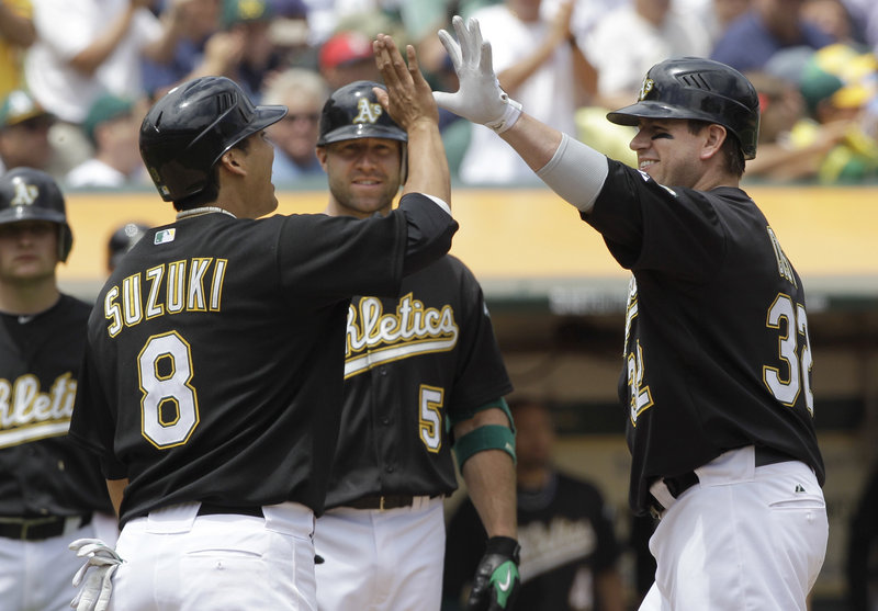 Jack Cust, right, is welcomed by Kurt Suzuki, left, and Kevin Kouzmanoff after hitting a two-run homer in the third inning for the Oakland Athletics.