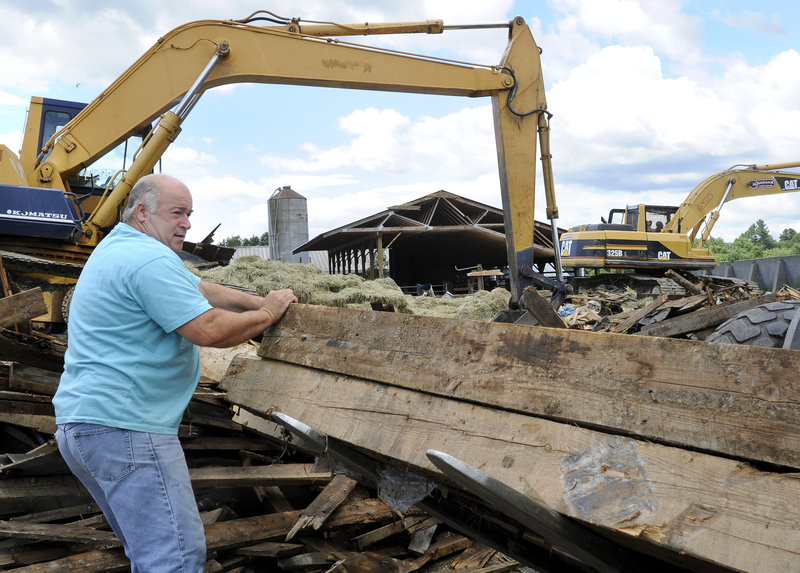Ed Benson salvages beams from his barn in Gorham on Thursday. The barn collapsed in a storm Wednesday night. "It's another day on the farm," said Ed Benson. "When you live on a farm, you understand these things happen."