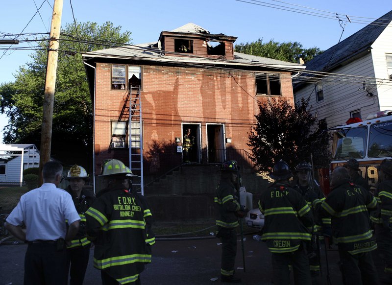 Fire officials gather after an apartment fire in Staten Island, N.Y., on Friday. Police said two children died of neck wounds and that a straight razor was found at the scene.