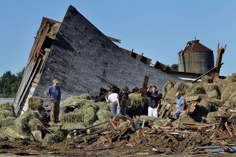 Workers and neighbors help clear debris from a barn destroyed by a severe storm at the Benson dairy farm in Gorham on Thursday.