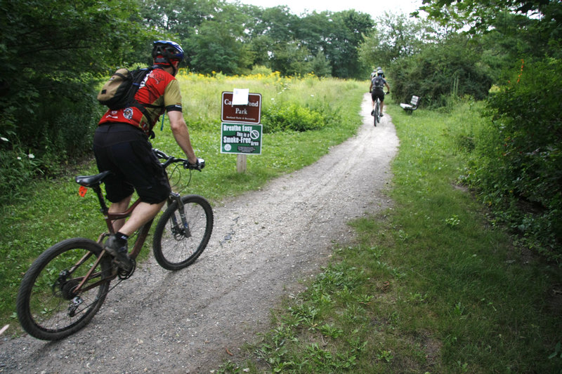 Mountain bikers enter Capisic Park near Macy Street on Friday. After a sewer project, which starts next month, is carried out, 600 new trees and shrubs will be planted in the park.