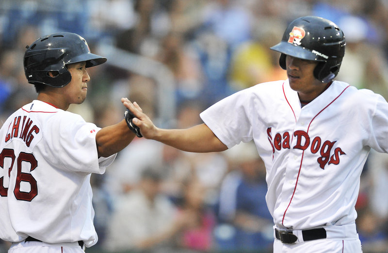 Chih-Hsien Chiang, right, of the Portland Sea Dogs is welcomed by Ray Chang after scoring in the second inning at Hadlock Field.