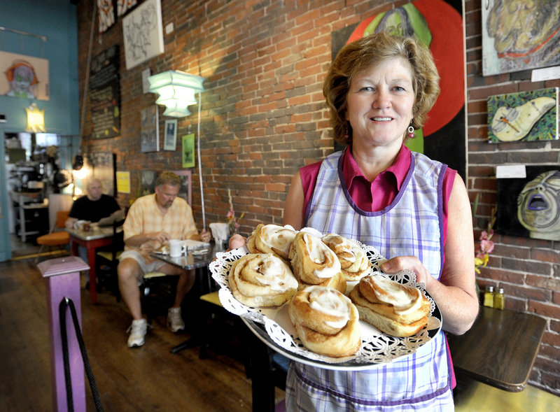 Linda Converse offers a trayful of cinnamon buns Monday at Oh Baby Cafe, the Biddeford restaurant she owns and operates with her daughter Ellen. The Converses, responding to increasing demand for morning meals, launched a full breakfast menu this week.