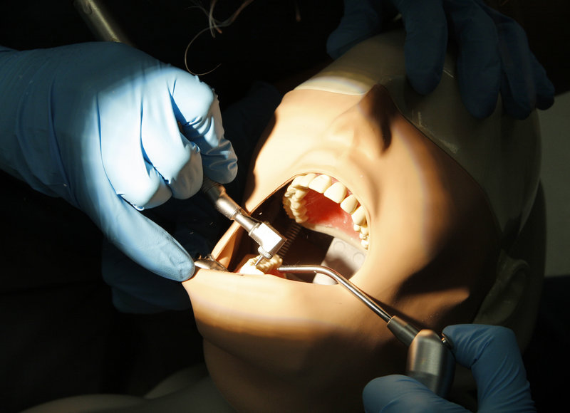 High school student Devin Ward uses a drill to remove decay in a tooth on a patient simulator in the dental clinic at the University of New England in Portland on Monday.