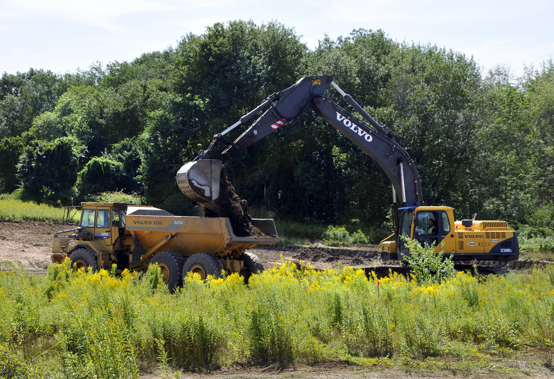 Workers create a holding pond as site preparation begins Tuesday on Eastman Meadows, a 40-acre project off Eastman Road near the Purpoodock Club in Cape Elizabeth.