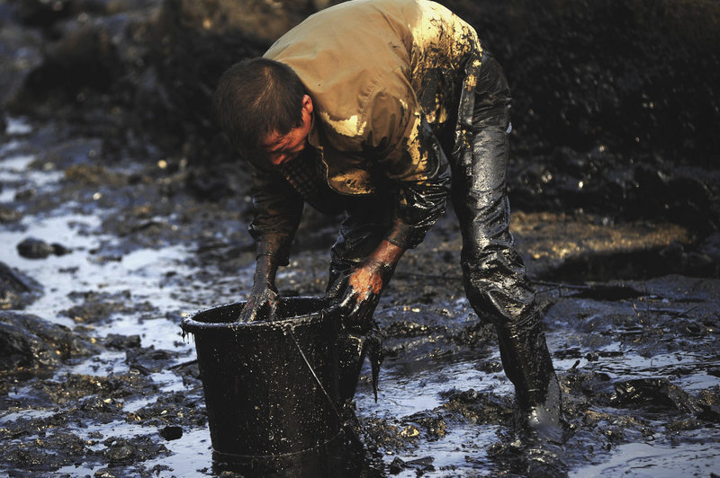 A worker cleans up oil in the Nantuo Fishing Harbor after a spill in Dalian in northeast China. The Chinese government says 461, 790 gallons have spilled, but an American oil spill expert puts the number at 18 to 27 million gallons.