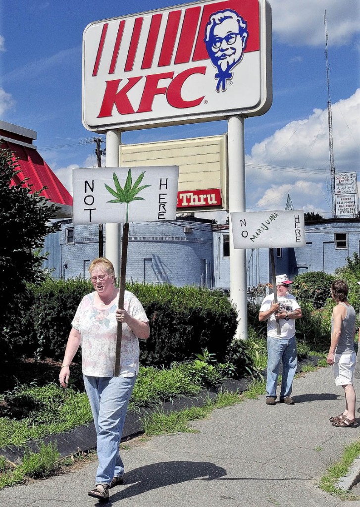 Beverly and Andrew Busque picket outside the former KFC restaurant in Waterville on Thursday. The site is where a proposed medical marijuana dispensary may be located. Beverly Busque said she approves of medical marijuana but is not in favor of the site, adjacent to her property.