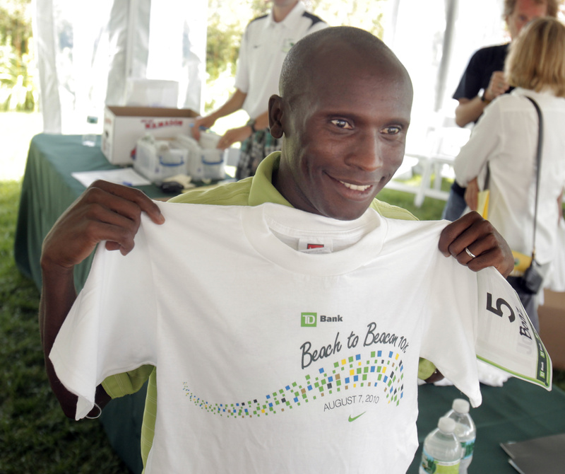 Boaz Cheboiywo holds up his Beach to Beacon shirt to see if it's the right size after the news conference for the TD Bank Beach to Beacon 10K road race in Cape Elizabeth on Friday.