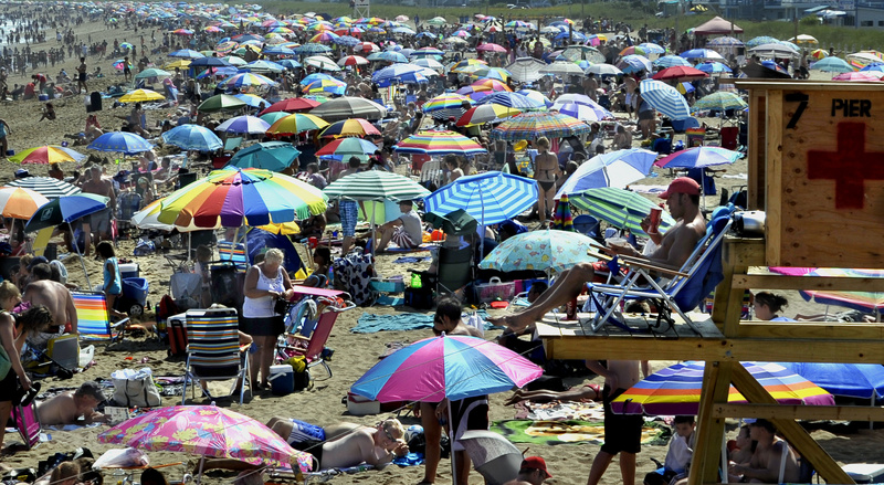 Perched above a sea of people and parasols, lifeguard Lance Timberlake monitors the scene at Old Orchard Beach on Tuesday. During the school year, Timberlake teaches American history and psychology at Sanford High School.