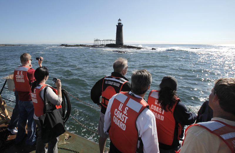 Bidders and their companions check out Ram Island Ledge Light on Thursday from a vessel provided by the Coast Guard. The seas were too rough for the boat to land on the rocky ledge and let bidders disembark to tour the interior, so they had to settle for viewing from a distance.