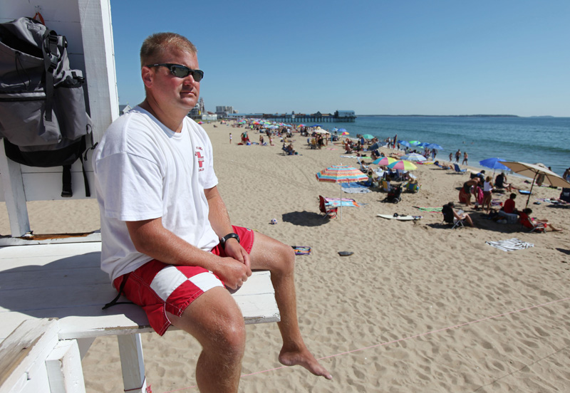 Old Orchard Beach chief lifeguard Keith Willett keeps an eye on swimmers today. Strong rip currents and crowded beaches are making it a busy summer for lifeguards in southern Maine and New Hampshire.