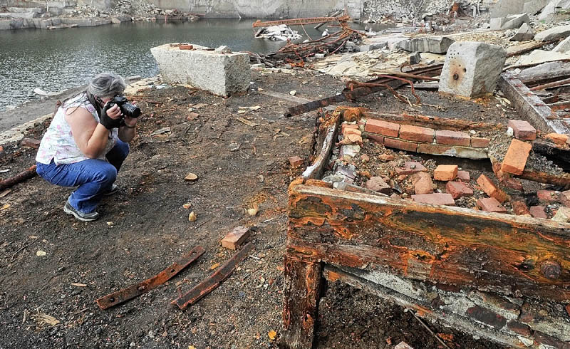Betty Blackman, of Edgecomb, takes pictures of rusty chains amongst the ruins on the floor of Stinchfield Quarry during a tour on Sunday in Hallowell.