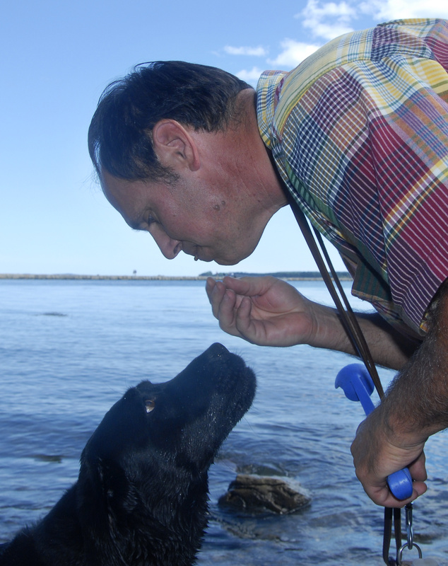 Ron Staschak of Rockport feeds a treat to his dog, Hazel, as they work on a trick for the Boatyard Dog competition.