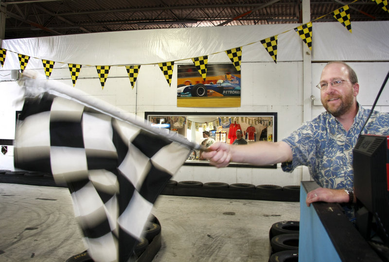 Reporter Ray Routhier waves the checkered flag to signal the end of a race at Maine Indoor Karting in Scarborough.