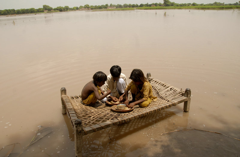 Pakistani children sit on a bed to eat in the flood-hit area of Qasim Bella on Saturday.