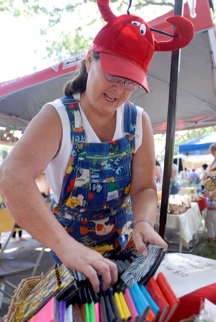 Linda Austin of Lisbon Falls arranges her “redneck wallets” – made of duct tape – at her booth at the eighth annual Festival of Nations in Deering Oaks on Saturday.