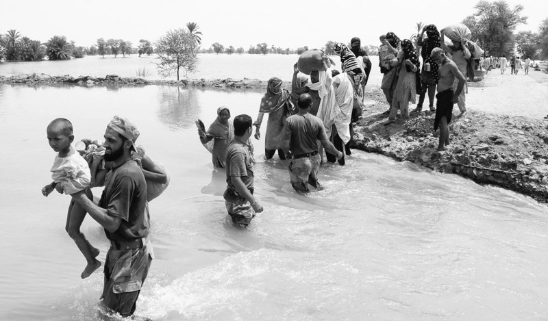 Pakistani soldiers help people to ford water as they flee their village flooded by heavy monsoon rains near Multan, Pakistan, on Sunday. More than 27,000 people remained trapped in one province, and 43 military helicopters and 100 boats were deployed to save them.