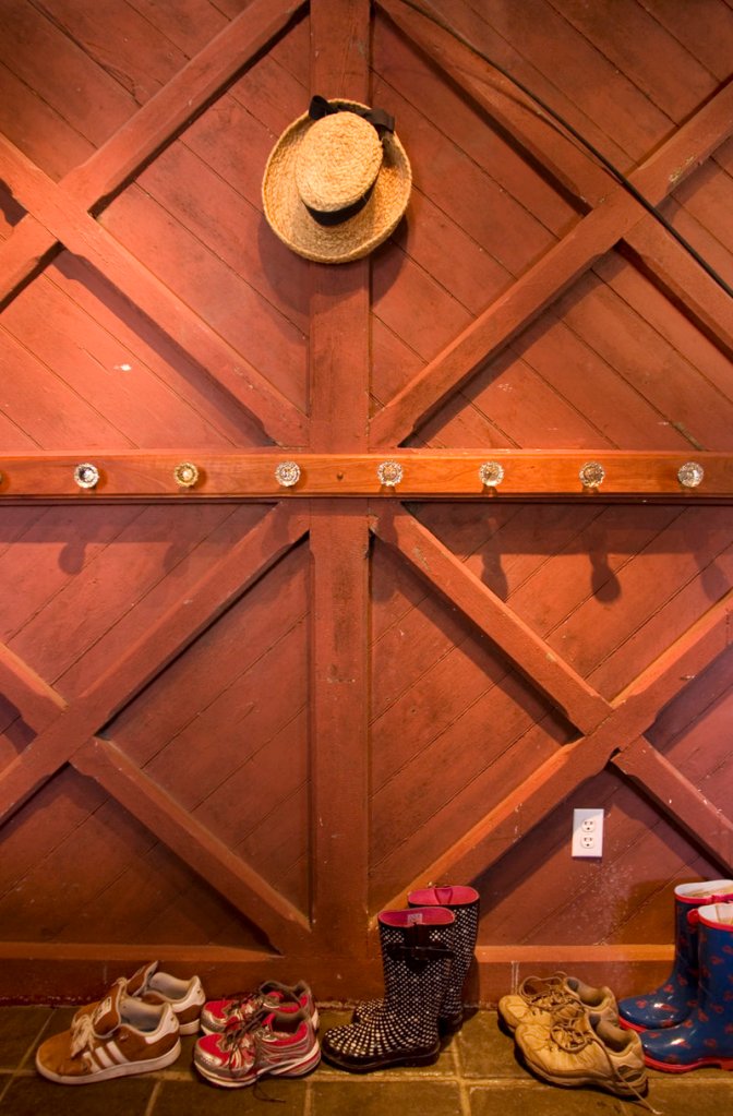 The wall of the mudroom is actually an old barn door. Coats and hats hang from antique doorknobs.