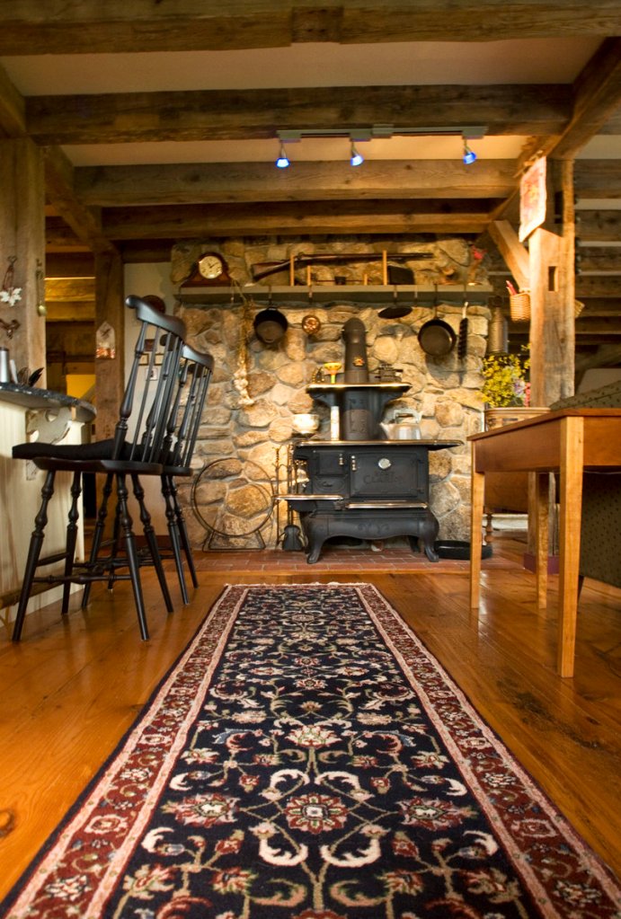 An old stove that has been refurbished sits against an interior stone wall between the kitchen and the living room.
