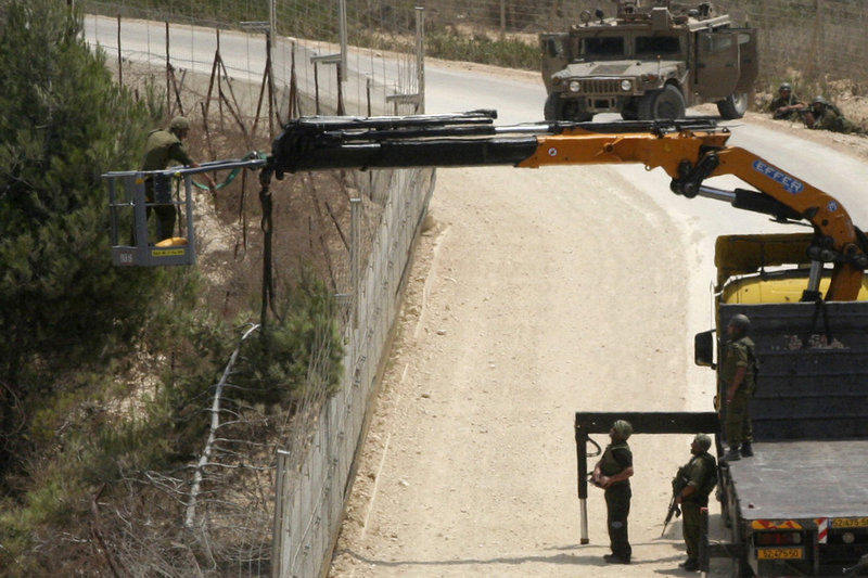 Israeli soldiers use a crane as they cut a tree Tuesday near the southern border village of Adeisseh, Lebanon. Israel and Lebanon each claimed the tree was in its territory. The sides exchanged fire, but the fighting ended after several hours.