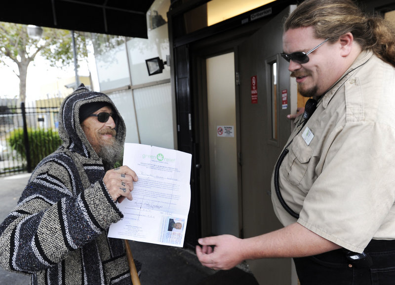Richard Lahrson of Berkeley, Calif., shows his doctor's recomendation and an identification card to Paul J. White before entering the Berkeley Patients Group clinic in Berkeley.