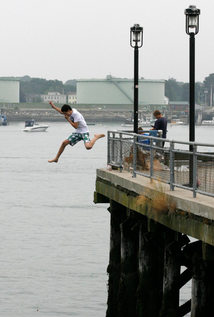 Nathan Delgado leaps from the Maine State Pier into Portland Harbor on Thursday. The city has experienced a string of above-normal temperatures going back to last November and includes the warmest March and April on record.