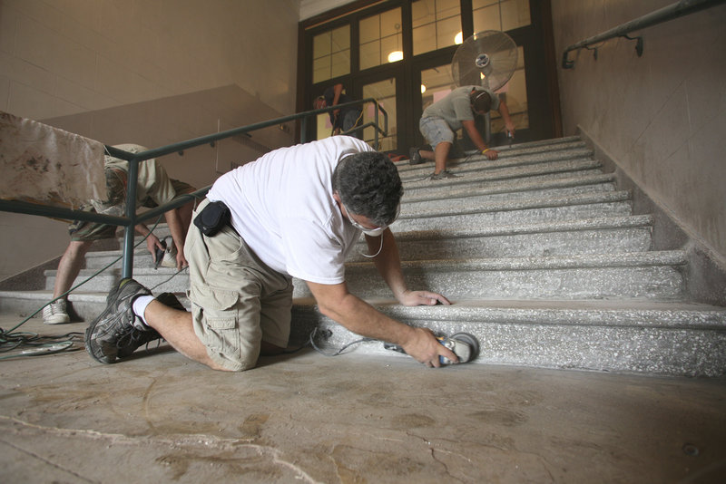 Tony Celeste, owner of Tony's Tile, uses a diamond grinder to remove excess cement during the restoration of the terrazzo tile stairs in the front entrance of Portland High School.
