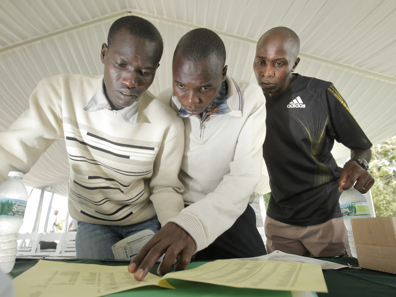 Joel Kemboi Kimurer, left, Stephen Kipkosgei-Kibet and Ed Muge check the list of runners for today's race. Muge will attempt to win the race for the third time.