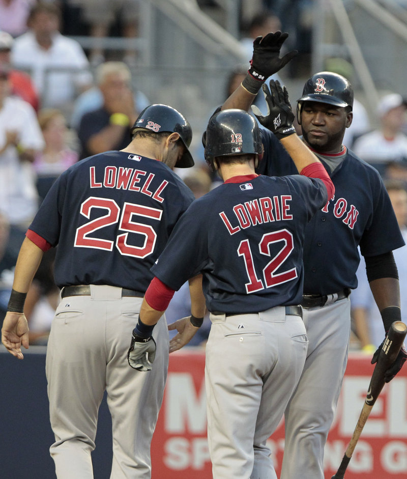 David Ortiz, right, is greeted by Mike Lowell and Jed Lowrie after scoring on Marco Scutaro’s two-run double in the second inning.