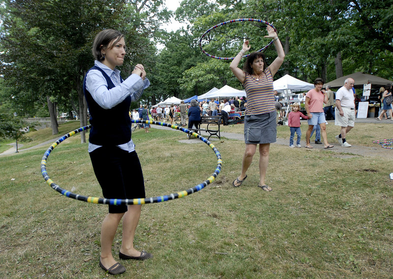 Hannah Fogg of Portland tries hula hooping with Tracy Tingley during the Portland Farmers Market at Deering Oaks on Saturday.