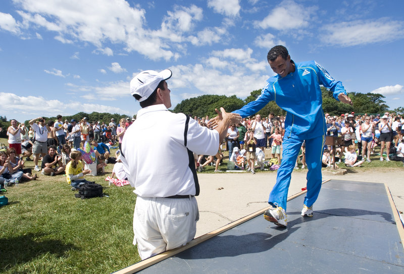 Gebre Gebremariam of Ethiopia climbs the ramp to the awards stage Saturday and receives a hand from Dave McGillivray, the race director, after becoming the first non-Kenyan Beach to Beacon winner since 1999. Gebremariam won $10,000.