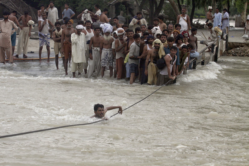 A man crosses a canal Monday with the help of a cable from an inundated bridge in Ghazi Gat, Pakistan. The number of people affected by Pakistan’s floods exceeds 13 million – more than the combined total of the 2004 tsunami and the 2005 Kashmir and 2010 Haitian earthquakes, the U.N. said.